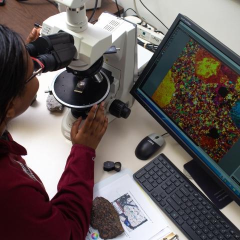 一名妇女通过显微镜观察细胞.