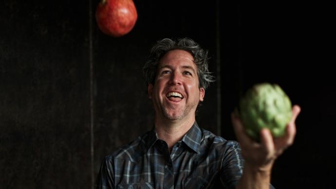 Hugh Daschbach juggles vegetables against a dark background