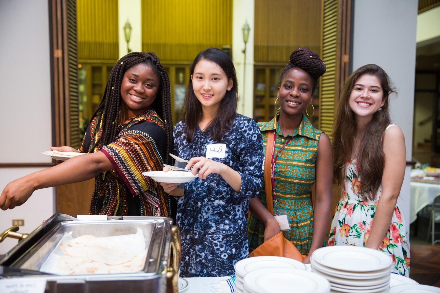 在查普曼大会堂举行的国际学生招待会上，四名妇女摆姿势微笑