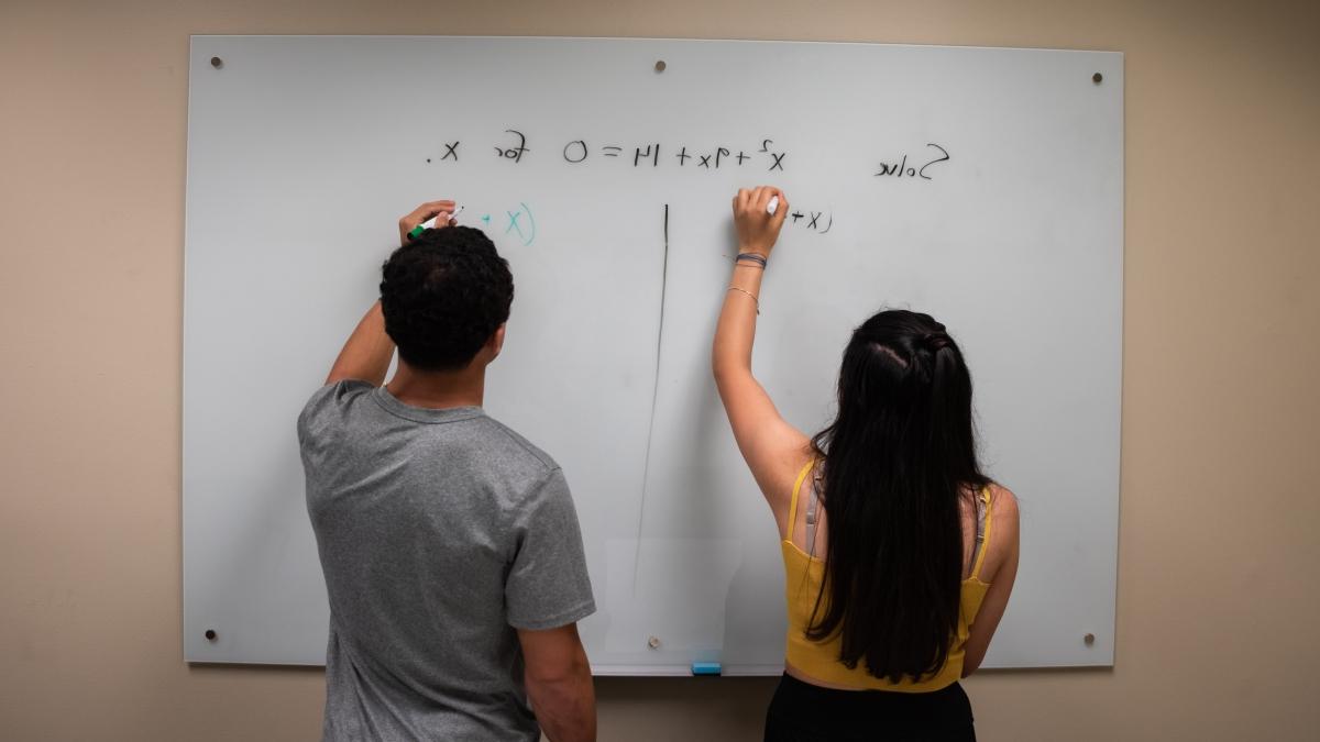 Two trinity 学生 brainstorming on a whiteboard